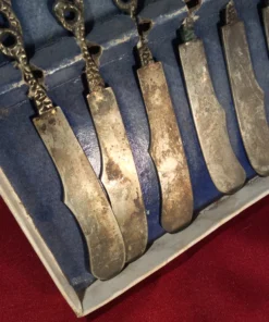 Close-up of lower half of dragon-handled butter knives showing vintage patina
