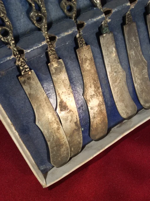 Close-up of lower half of dragon-handled butter knives showing vintage patina
