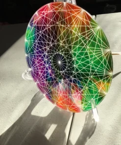 Side angle of rainbow sacred geometry disc catching the light