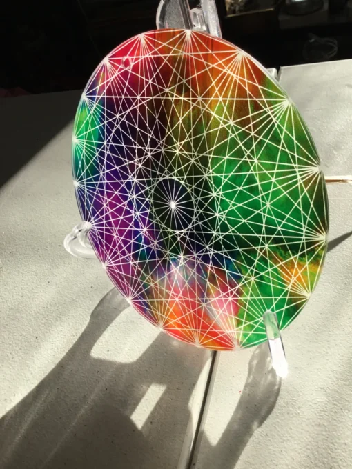 Side angle of rainbow sacred geometry disc catching the light