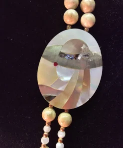 Detailed view of mother-of-pearl inlay pendant depicting a stylized woman in a hat. 01