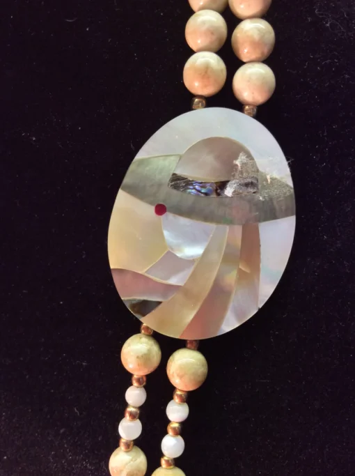 Detailed view of mother-of-pearl inlay pendant depicting a stylized woman in a hat. 01