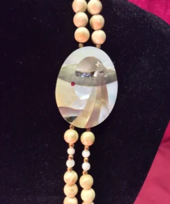 Detailed view of mother-of-pearl inlay pendant depicting a stylized woman in a hat.