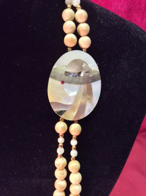 Detailed view of mother-of-pearl inlay pendant depicting a stylized woman in a hat.
