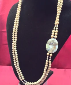 Vintage beaded necklace with double strands and shell inlay pendant on display bust.