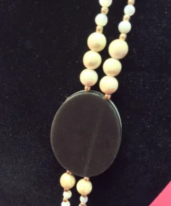 Smooth black backing of oval shell pendant shown from the reverse side.
