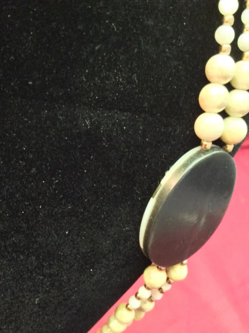 Side view of the pendant revealing shell inlay depth and curved finish.
