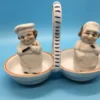 Vintage ceramic salt and pepper shakers shaped like winking bakers in double handled caddy