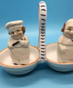 Vintage ceramic salt and pepper shakers shaped like winking bakers in double handled caddy