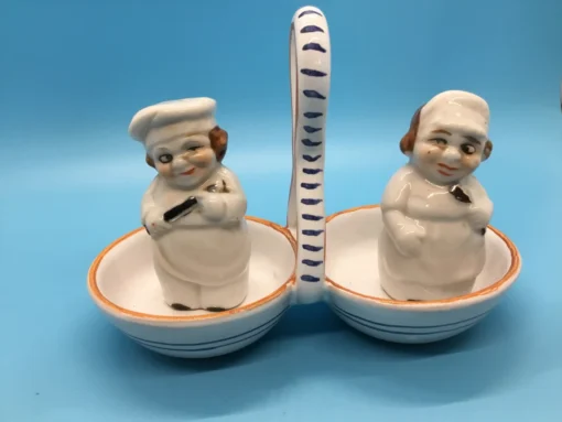 Vintage ceramic salt and pepper shakers shaped like winking bakers in double handled caddy
