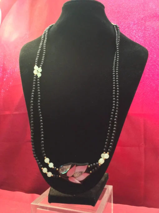 Full necklace on black display with pink backdrop