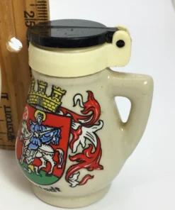 Close-up of black-lidded Neustadt pepper shaker with crest and handle