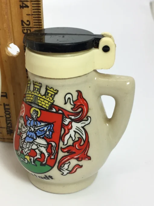 Close-up of black-lidded Neustadt pepper shaker with crest and handle