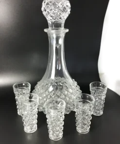 Angled view of vintage crystal-style decanter with six matching glasses