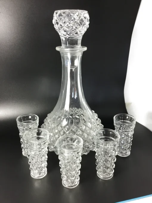 Angled view of vintage crystal-style decanter with six matching glasses