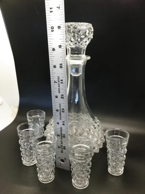 Ruler measuring height of vintage crystal-style decanter with six glasses